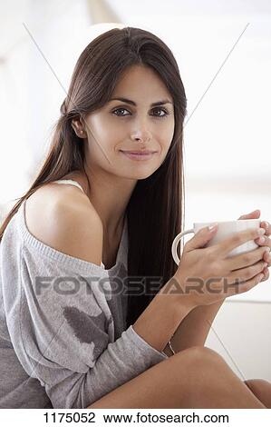 Stock Image - Comfortable woman holding coffee cup. Fotosearch