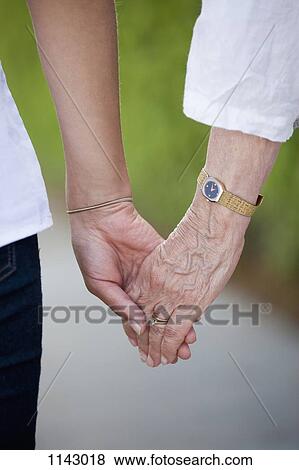 Detail of a senior woman and a young woman holding hands View Large Photo Image Stock Photo - Detail of a senior woman and a young woman holding hands. Fotosearch
