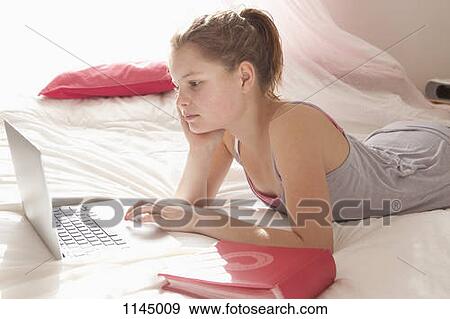Girl on bed doing homework View Large Photo Image Stock Photo - Girl on bed doing homework. Fotosearch