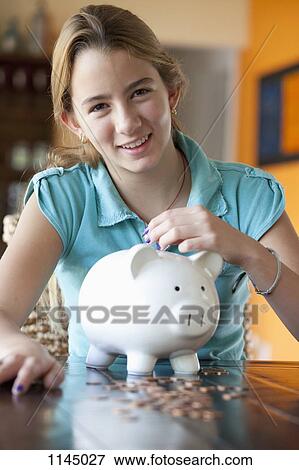 Stock Photo - Girl puts coin in piggy bank. Fotosearch
