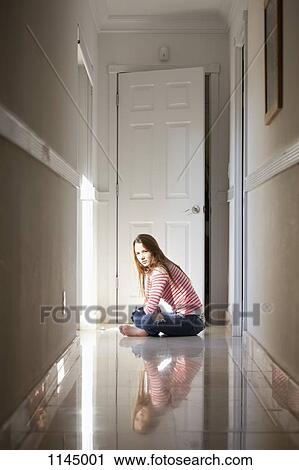 Stock Image - Girl sitting cross-legged in hallway. Fotosearch