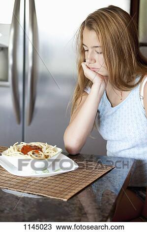 Stock Image - Girl unhappy with her spaghetti meal. Fotosearch