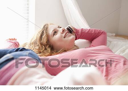 Girls on bed on the phone View Large Photo Image Picture - Girls on bed on the phone. Fotosearch