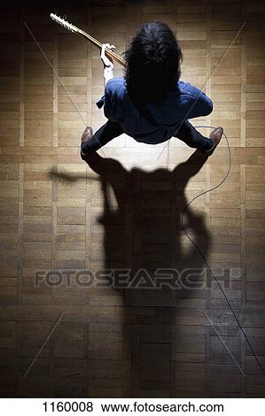 Guitarist in spotlight creating a shadow symbol of the 'sign of the horns' View Large Photo Image Stock Photo - Guitarist in spotlight creating a shadow symbol of the 'sign of the horns'. Fotosearch