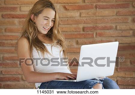 Stock Image - Happy girl using laptop. Fotosearch