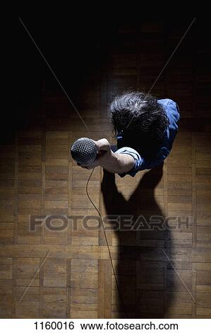 High angle view of man holding mic up to camera View Large Photo Image Stock Photograph - High angle view of man holding mic up to camera. Fotosearch