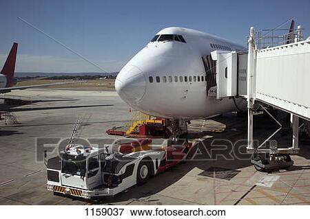 Jumbo jet attached to boarding bridge with tug in front View Large Photo Image Stock Photo - Jumbo jet attached to boarding bridge with tug in front. Fotosearch
