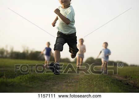 Low view of a boy running in a field with other children behind View Large Photo Image Stock Image - Low view of a boy running in a field with other children behind. Fotosearch