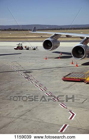 Stock Photo - Luggage trolley moving away from jet. Fotosearch