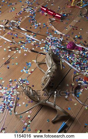 Stock Photograph - Metallic strappy heels, confetti and streamers littering a hardwood floor. Fotosearch