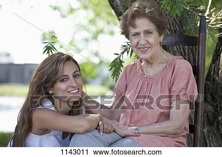 Portrait of a senior woman and a young woman sitting together outside View Large Photo Image Stock Image - Portrait of a senior woman and a young woman sitting together outside. Fotosearch