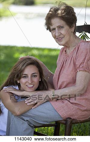 Portrait of a senior woman and a young woman sitting together outside View Large Photo Image Stock Image - Portrait of a senior woman and a young woman sitting together outside. Fotosearch