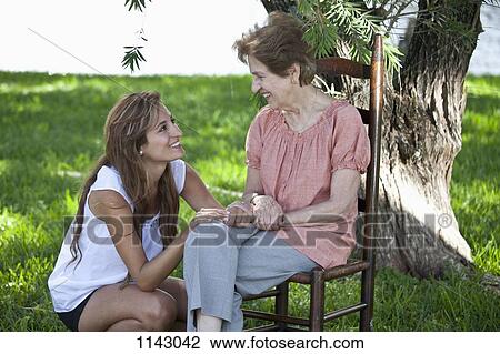 Portrait of a senior woman and a young woman sitting together outside View Large Photo Image Stock Image - Portrait of a senior woman and a young woman sitting together outside. Fotosearch