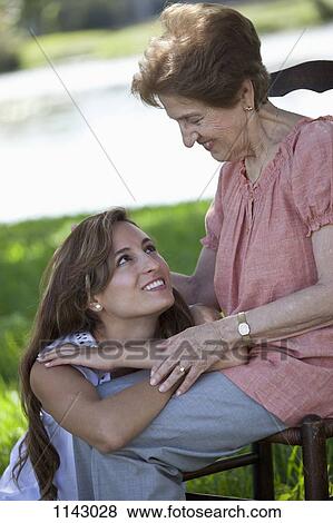 Stock Photo - Portrait of a senior woman and a young woman sitting together outside. Fotosearch