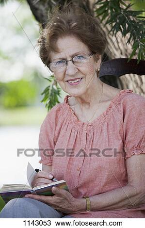 Portrait of a senior woman writing in a book View Large Photo Image Stock Image - Portrait of a senior woman writing in a book. Fotosearch