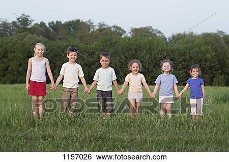 Stock Photograph - Portrait of children holding hands in a field. Fotosearch