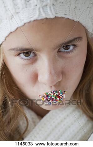 Stock Image - Portrait of girl with abundance of pins in mouth. Fotosearch
