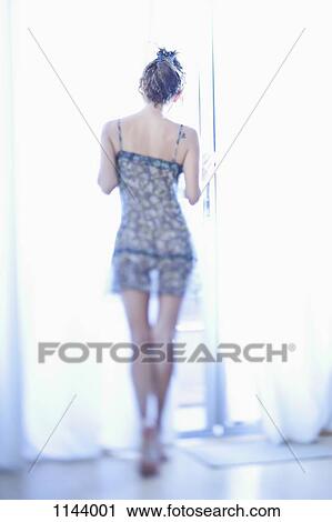 Rear view of a woman in see through nightgown looking out a window View Large Photo Image Stock Image - Rear view of a woman in see through nightgown looking out a window. Fotosearch