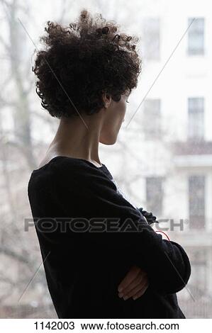 Side view of a woman looking through a window View Large Photo Image Stock Image - Side view of a woman looking through a window. Fotosearch
