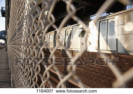 Train seen through wire fence which separates the pedestrian walkway on Manhattan Bridge View Large Photo Image Stock Photo - Train seen through wire fence which separates the pedestrian walkway on Manhattan Bridge. Fotosearch