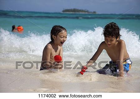 Two boys playing in the surf, View Large Photo Image Stock Image - Two boys playing in the surf, . Fotosearch