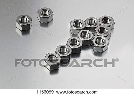 Stock Photo - Two metal nuts next to a group of nuts arranged into an arrow sign. Fotosearch
