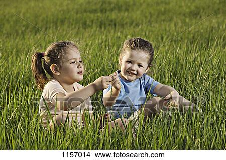Picture - Two young girls sitting in a field. Fotosearch