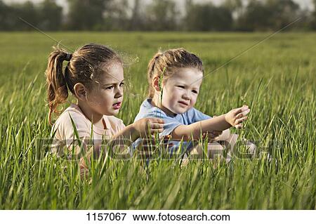 Stock Photo - Two young girls sitting in a field. Fotosearch