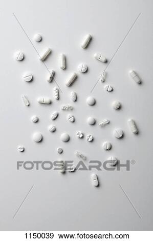 Stock Photo - Various white pills and capsules spread out on a white surface. Fotosearch