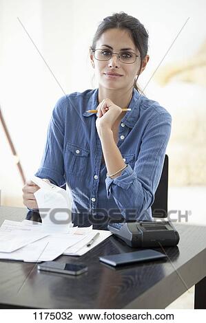 Stock Image - Woman at desk calculating her receipts . Fotosearch