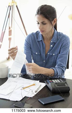 Woman at desk looking at receipts View Large Photo Image Stock Image - Woman at desk looking at receipts . Fotosearch
