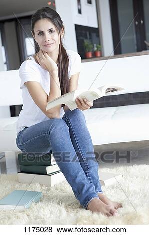 Woman at home sitting on books and reading View Large Photo Image Stock Photo - Woman at home sitting on books and reading. Fotosearch