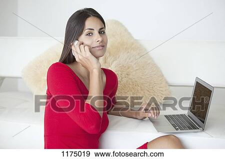 Woman in red on phone and with laptop View Large Photo Image Stock Photo - Woman in red on phone and with laptop. Fotosearch