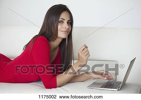 Woman in red on sofa with laptop View Large Photo Image Stock Image - Woman in red on sofa with laptop. Fotosearch
