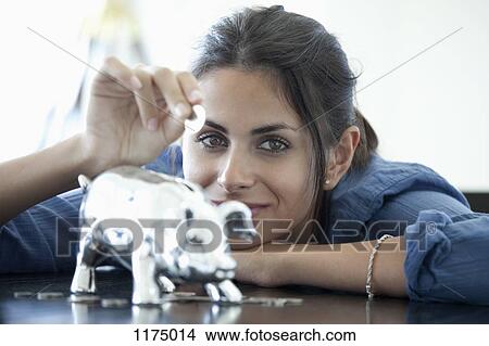Woman putting coin into piggy bank View Large Photo Image Picture - Woman putting coin into piggy bank. Fotosearch