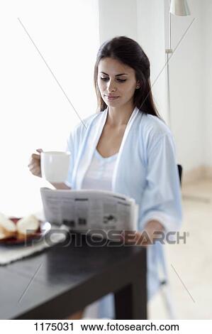 Stock Image - Woman reading the morning newspaper. Fotosearch