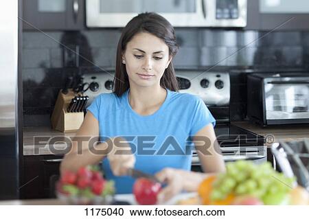 Stock Image - Woman slicing apple in kitchen. Fotosearch