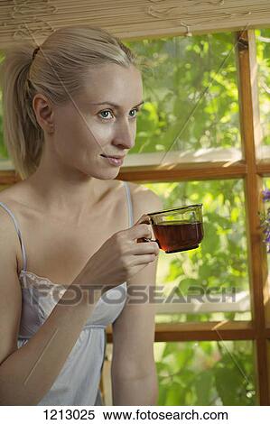 A beautiful woman in a nightie sitting by a window drinking tea View Large Photo Image Stock Photography - A beautiful woman in a nightie sitting by a window drinking tea. Fotosearch
