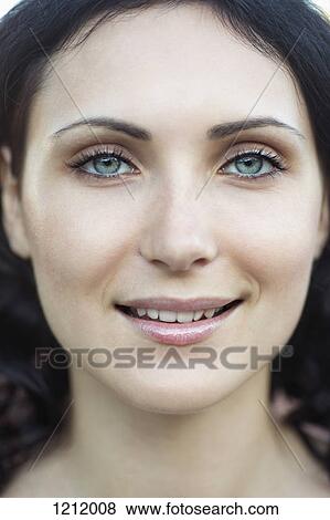 Stock Photo - A beautiful young woman smiling into the camera, close-up of face. Fotosearch
