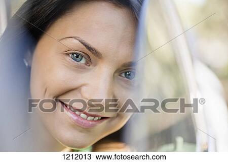 A beautiful young woman smiling while peeking through a car window View Large Photo Image Stock Image - A beautiful young woman smiling while peeking through a car window. Fotosearch