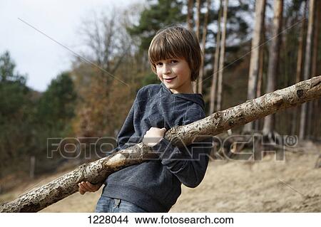 A boy carrying a large branch in a wooded area View Large Photo Image Picture - A boy carrying a large branch in a wooded area. Fotosearch