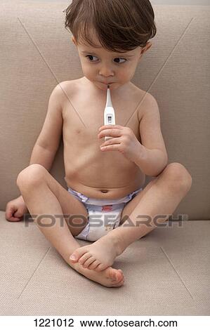 Stock Image - A boy holding a thermometer in his mouth. Fotosearch