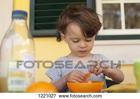 A boy preparing to eat a slice of fresh orange for breakfast View Large Photo Image Stock Photo - A boy preparing to eat a slice of fresh orange for breakfast. Fotosearch