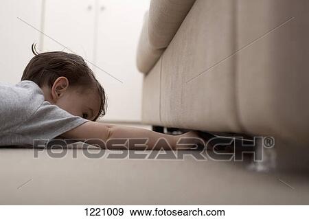 A boy reaching under a sofa to retrieve something View Large Photo Image Stock Photo - A boy reaching under a sofa to retrieve something. Fotosearch