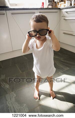 A boy standing in a domestic kitchen playing with sunglasses View Large Photo Image Picture - A boy standing in a domestic kitchen playing with sunglasses. Fotosearch