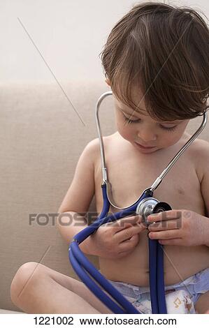 Stock Image - A boy wearing only diapers, playing with a stethoscope. Fotosearch