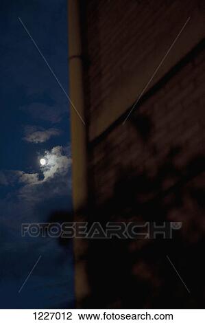 Stock Image - A building with the moon in the night sky. Fotosearch