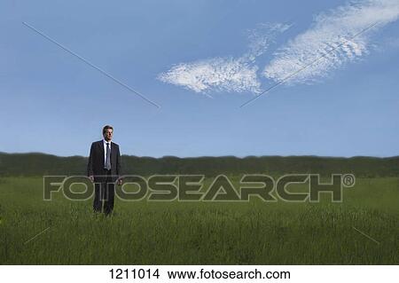 A businessman walking through a field in a remote location View Large Photo Image Picture - A businessman walking through a field in a remote location. Fotosearch