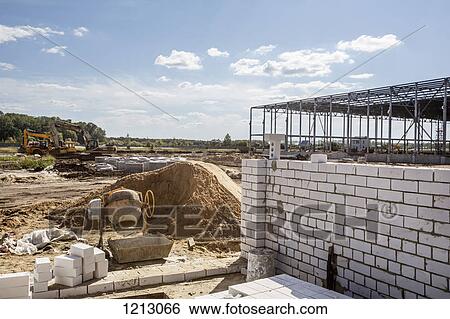 A cement mixer and brick wall in front of a construction frame at a construction site View Large Photo Image Stock Photograph - A cement mixer and brick wall in front of a construction frame at a construction site. Fotosearch