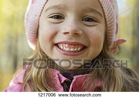 Stock Photograph - A cheerful young girl wearing a pink knit hat and grinning . Fotosearch